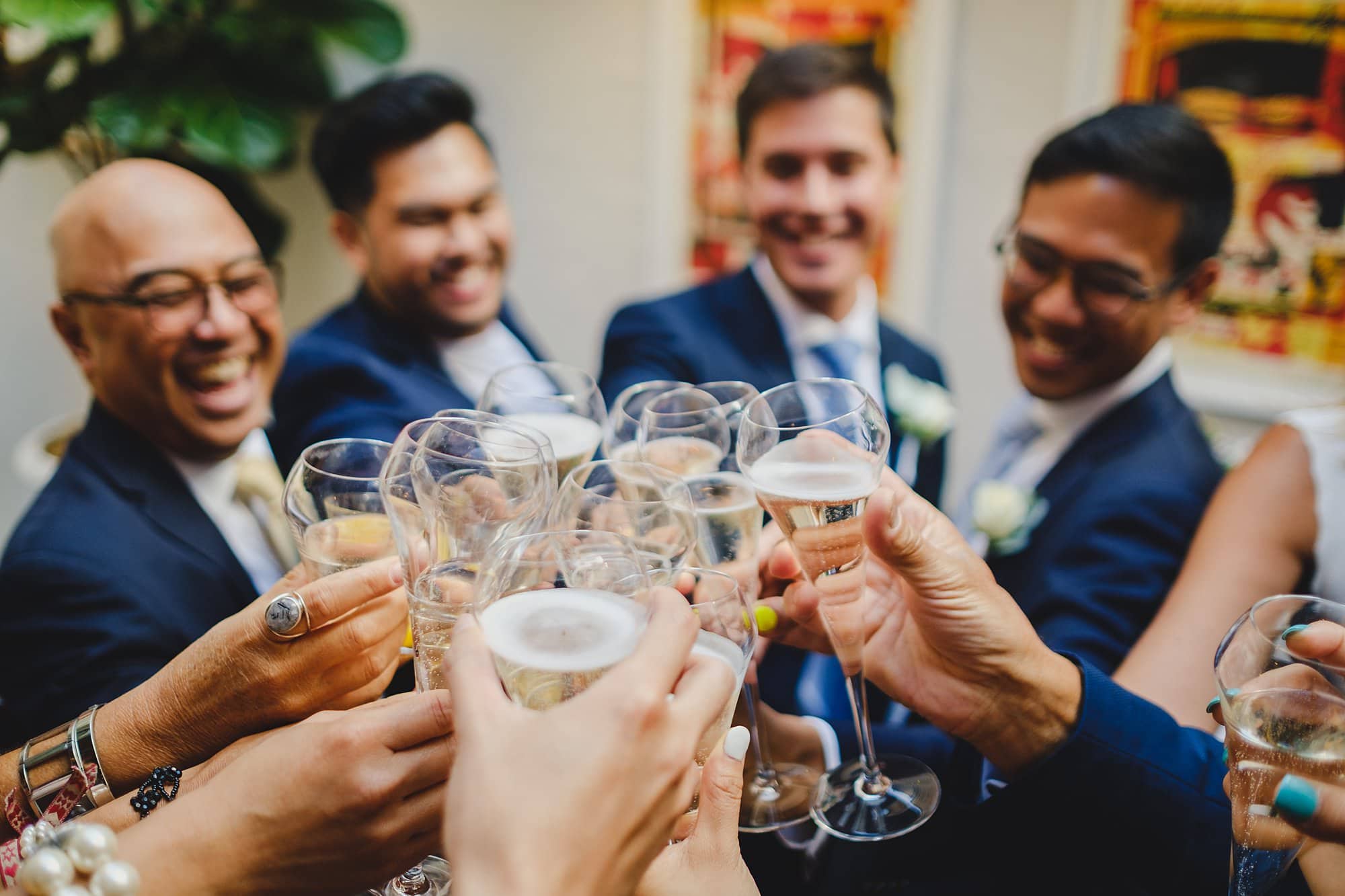 London wedding photography of the grooms and guests bringing their Champagne glasses together - cheers!