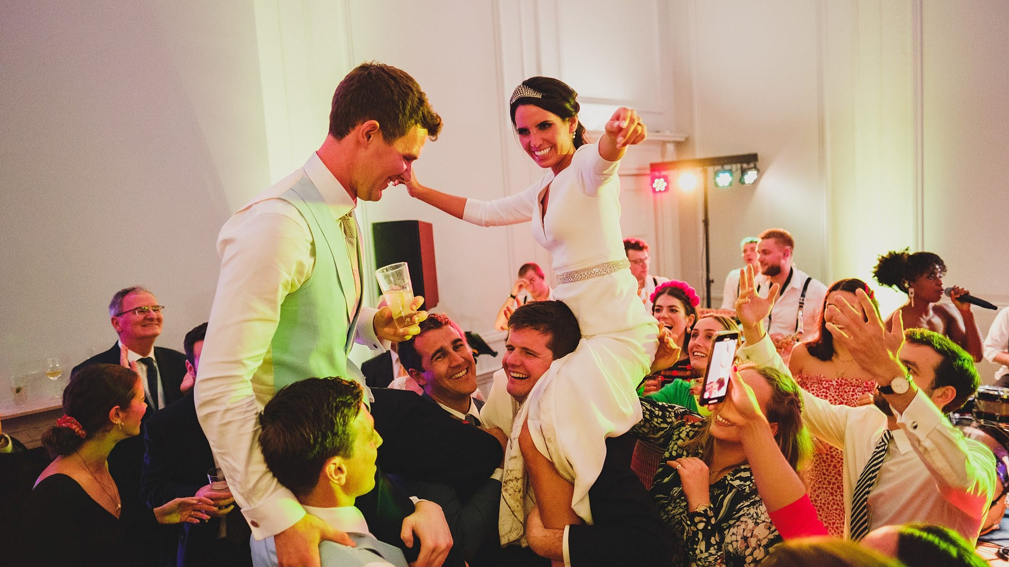 bride and groom carried onto the dancefloor on their guests shoulders