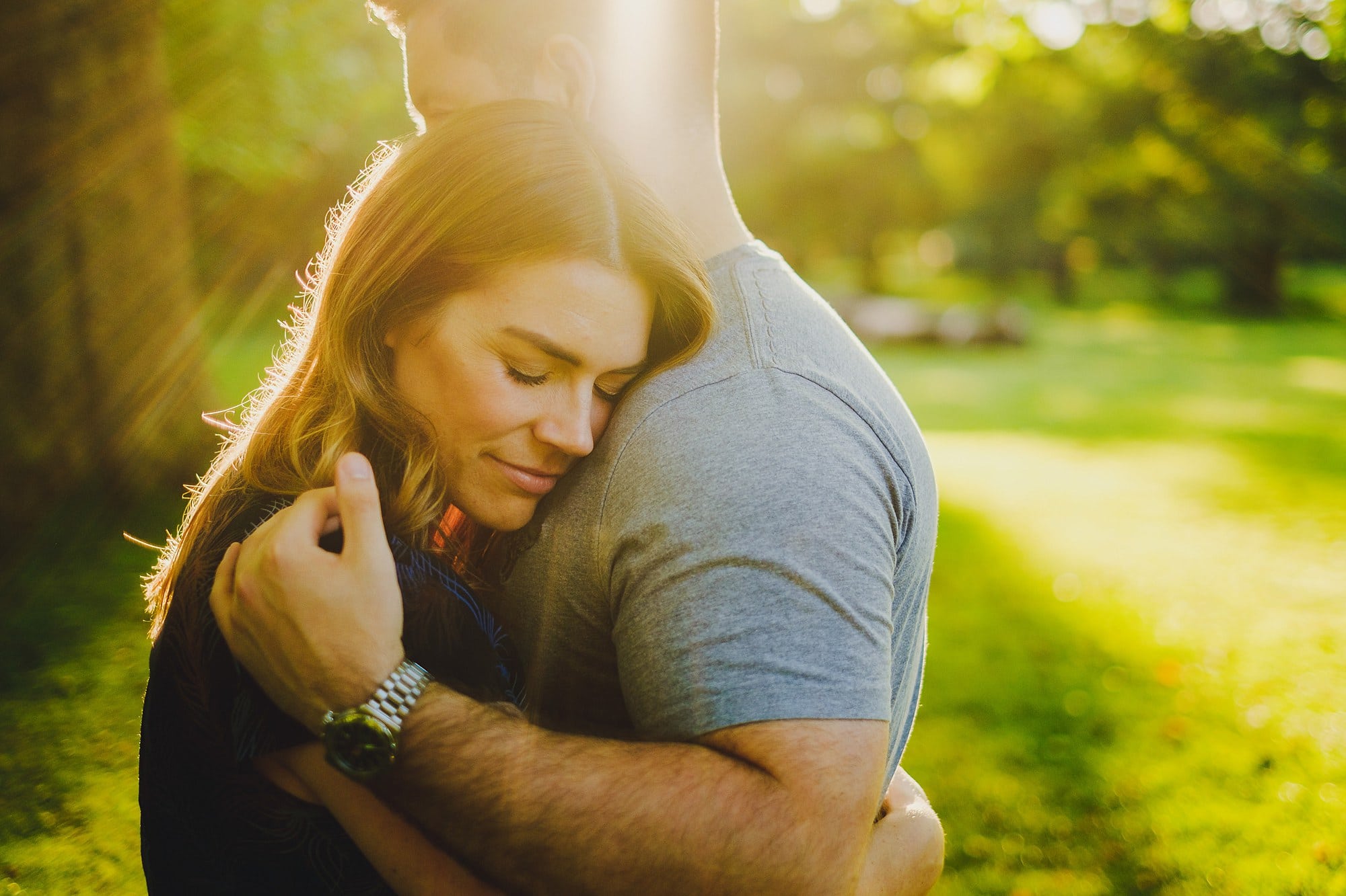 a couple embrace in the rays of evening sun in bushy park during a London engagement photography session