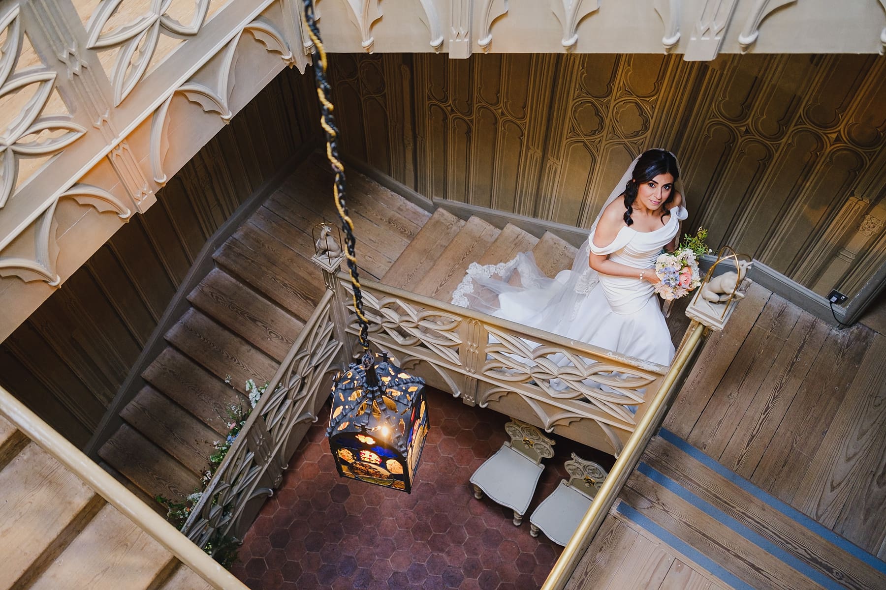 Bride posing on the stairwell inside Strawberry Hill House, Groom greeting guests with a hug, by Strawberry Hill House wedding photographer Owen Billcliffe